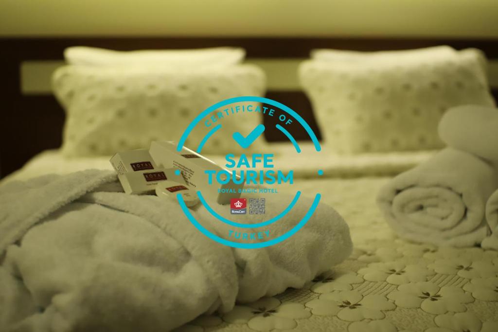 un osito de peluche sentado en una cama con un cartel. en Royal Bilgic Hotel, en Kırklareli