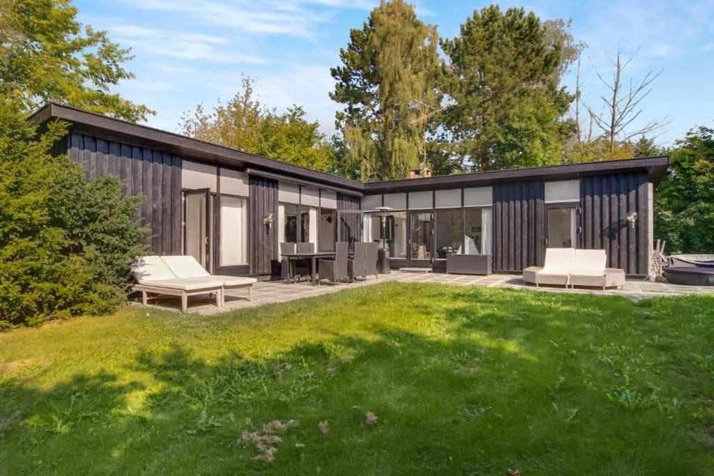 uma casa moderna com um quintal verde em Cozy summer house 50 meter from the beach, 89 m² em Dronningmølle