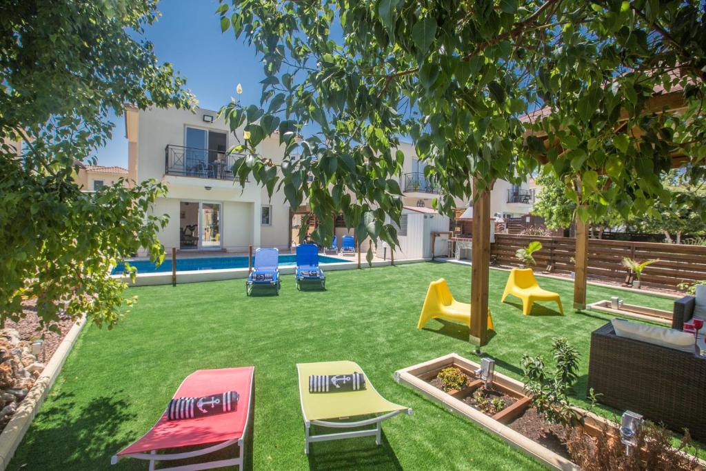 einen Garten mit Stühlen und einem Spielplatz in der Unterkunft Ariella Villa in Protaras