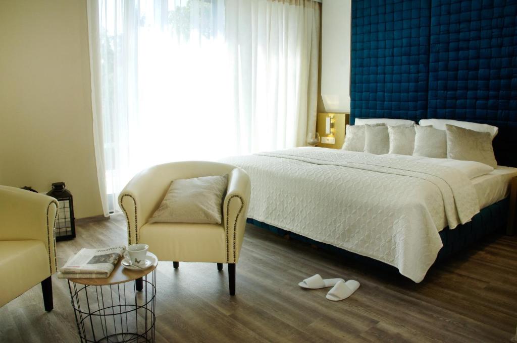 ケルステルバッハにあるHotel Athen Kelsterbach Frankfurt Airportのベッドルーム(大きな白いベッド1台、椅子付)
