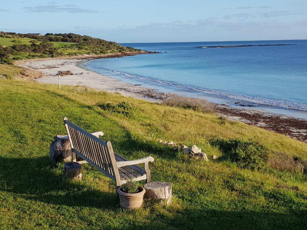 Emu Bay的住宿－tu Emuz Stone Beachfront Villa, Emu Bay, Kangaroo Is，坐在山丘上的长凳,俯瞰海滩