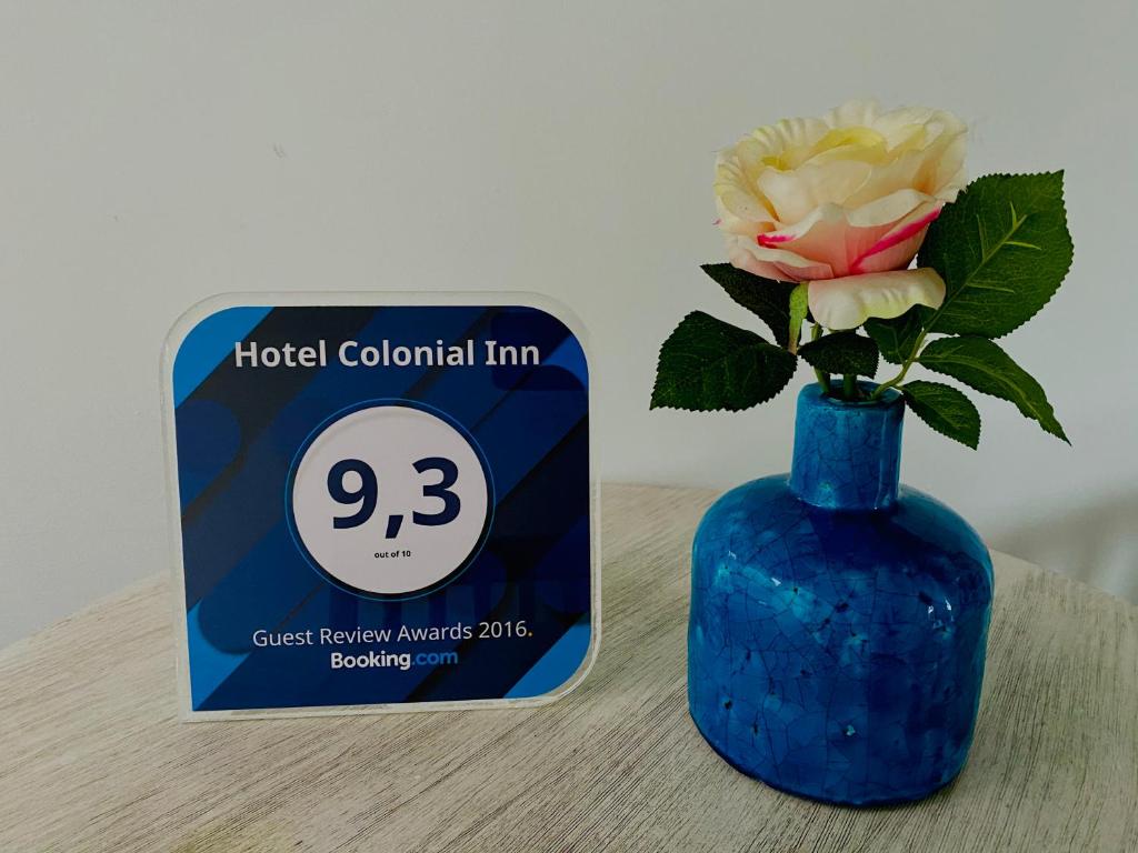 a blue vase with a flower in it next to a sign at Hotel Maceo 55 - Colonial Inn in Bogotá