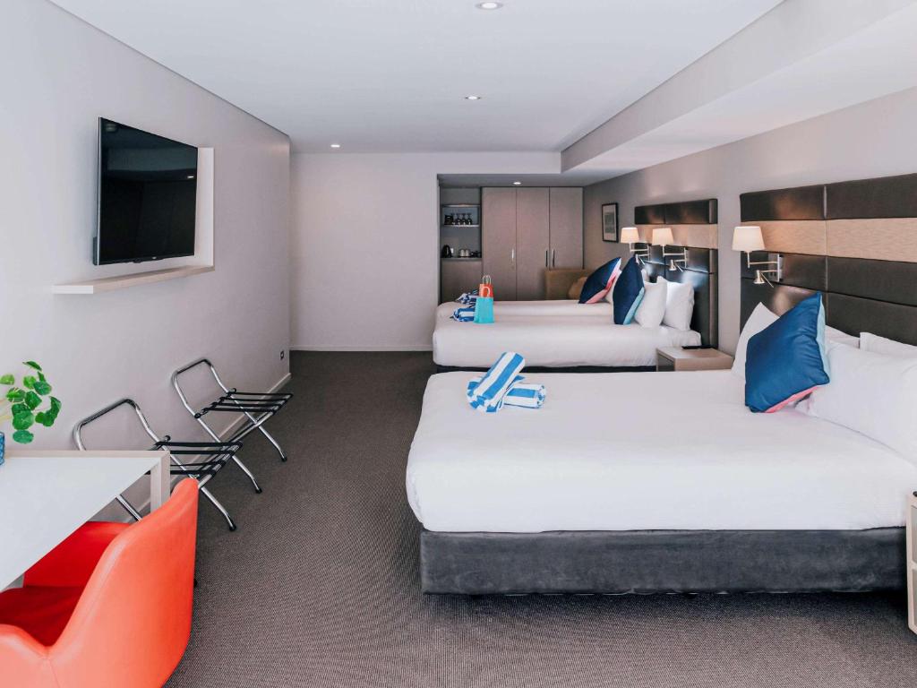 a hotel room with two beds and a tv at Novotel Newcastle Beach in Newcastle