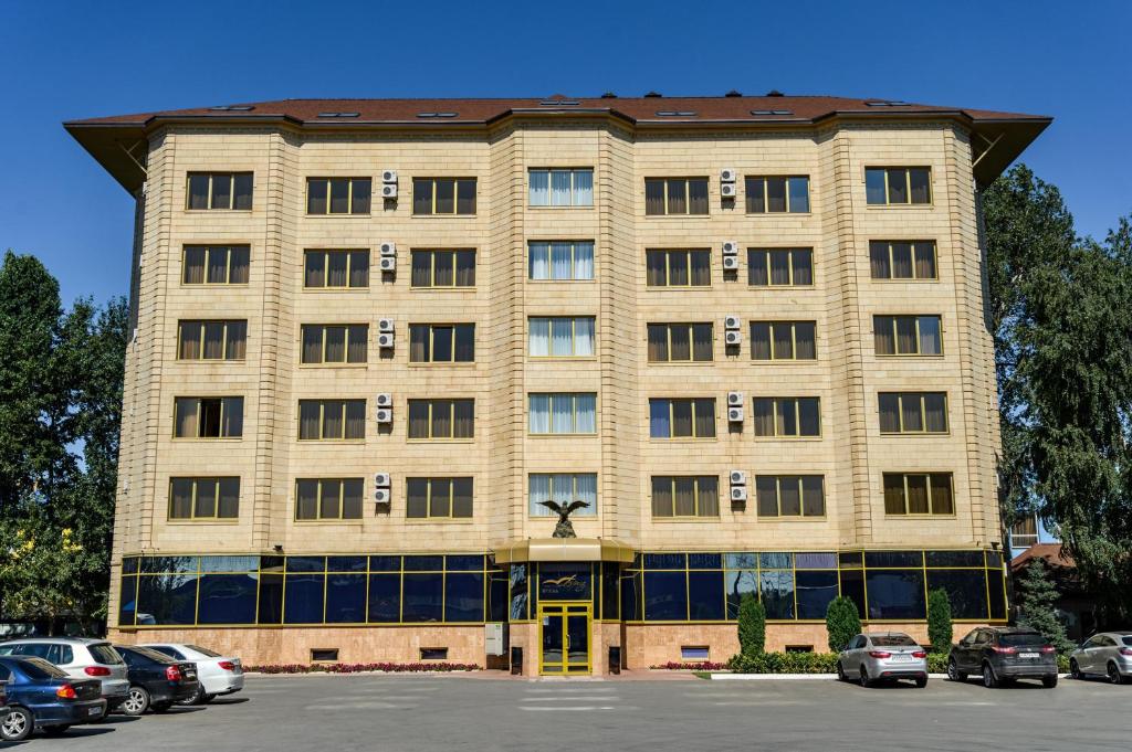 a large building with cars parked in a parking lot at Hotel Briz in Orenburg