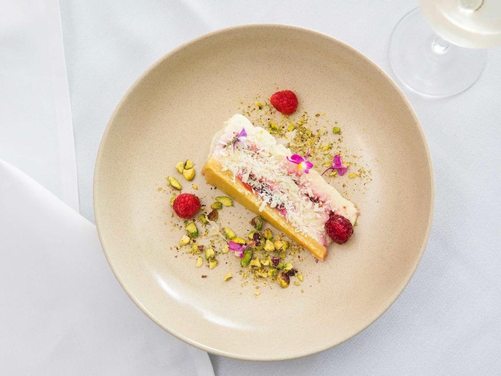 a plate with a piece of cake with berries on it at Novotel Newcastle Beach in Newcastle