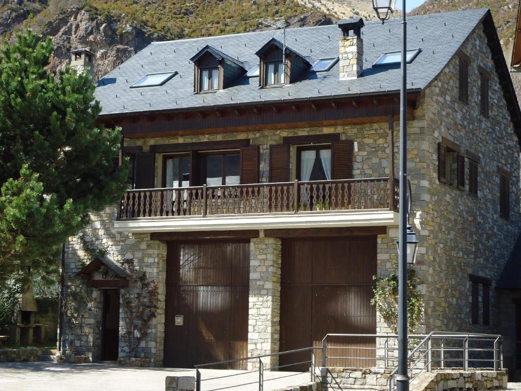 uma grande casa de pedra com uma varanda e uma garagem em Casa Rural la Comella em Barruera