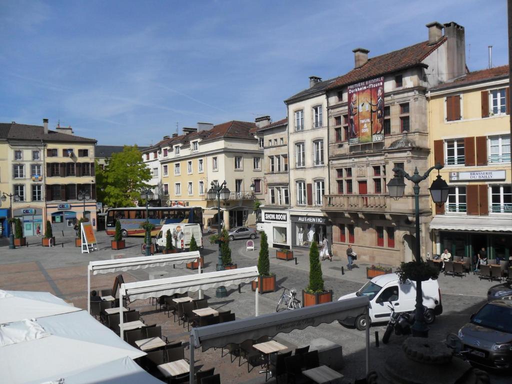 une rue de la ville avec des bâtiments, des tables et des chaises dans l'établissement Hotel La Basilique, à Épinal