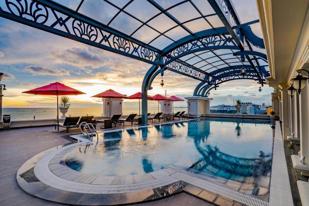 una piscina con mesas y sombrillas en un edificio en AVS Hotel Phu Quoc en Phu Quoc