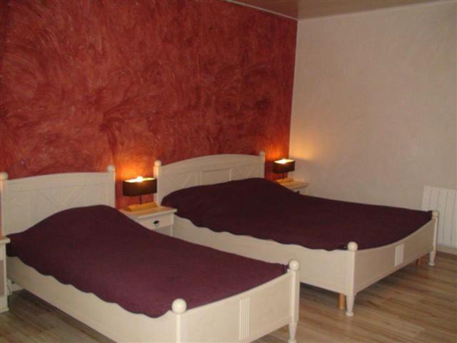 two beds in a bedroom with red walls at Chambres d'hôtes La Rêvaillante in Bourges