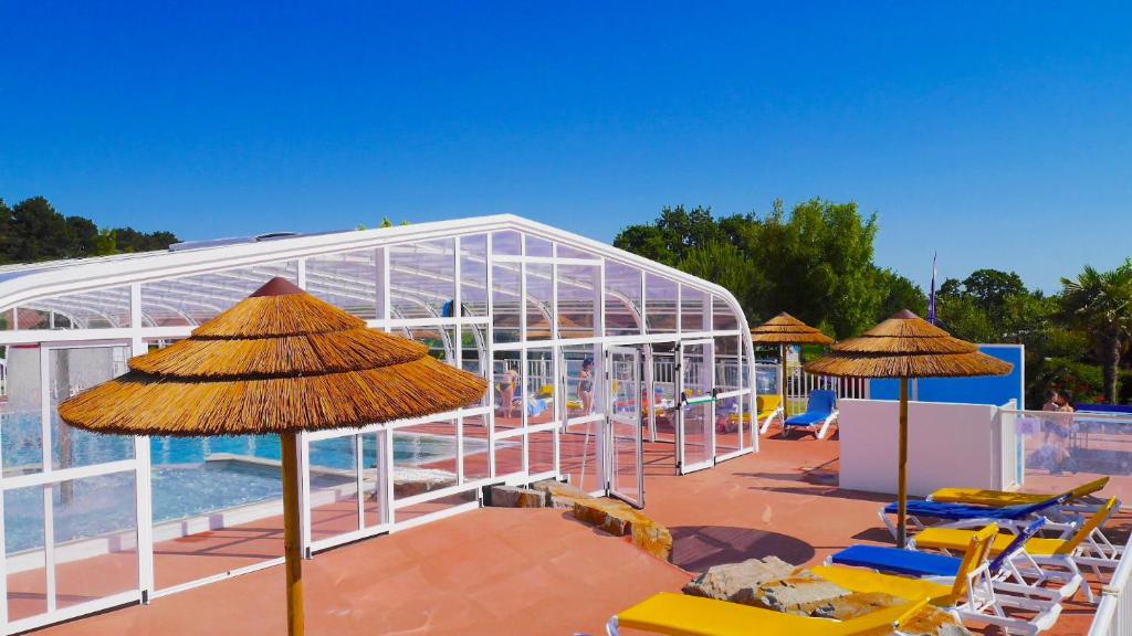 een resort met stoelen en parasols en een zwembad bij Camping Les Brillas in Les Moutiers