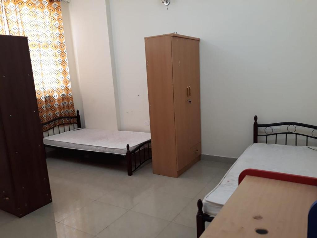 a small room with two beds and a cabinet at Affordable Bed Space in Fujairah in Fujairah