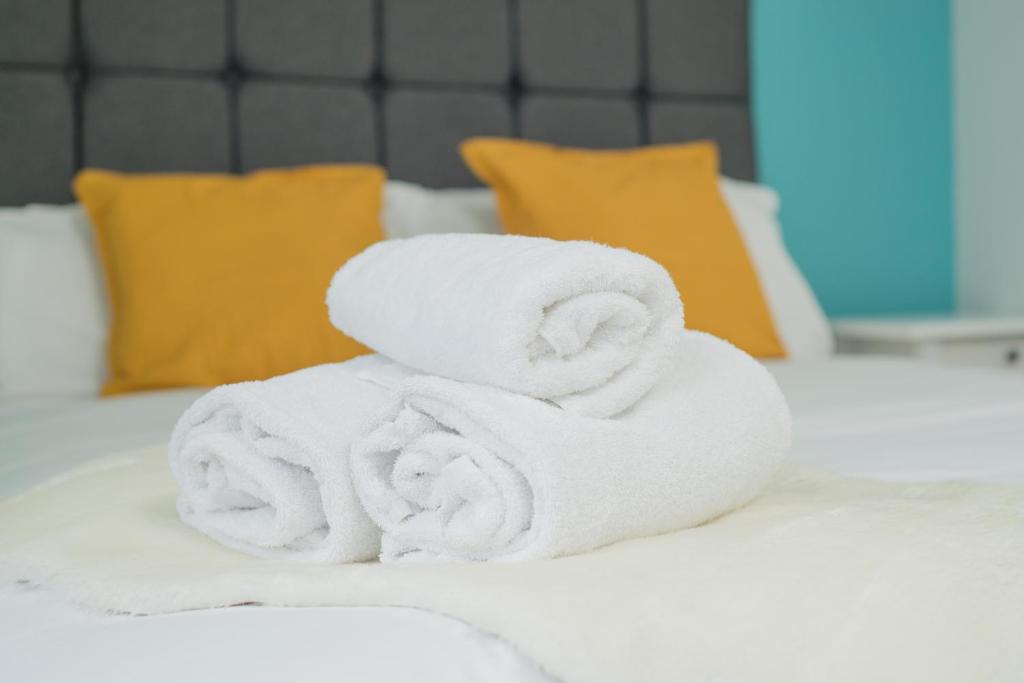 een stapel handdoeken bovenop een bed bij TLK Apartments & Hotel - Beckenham High Street in Beckenham