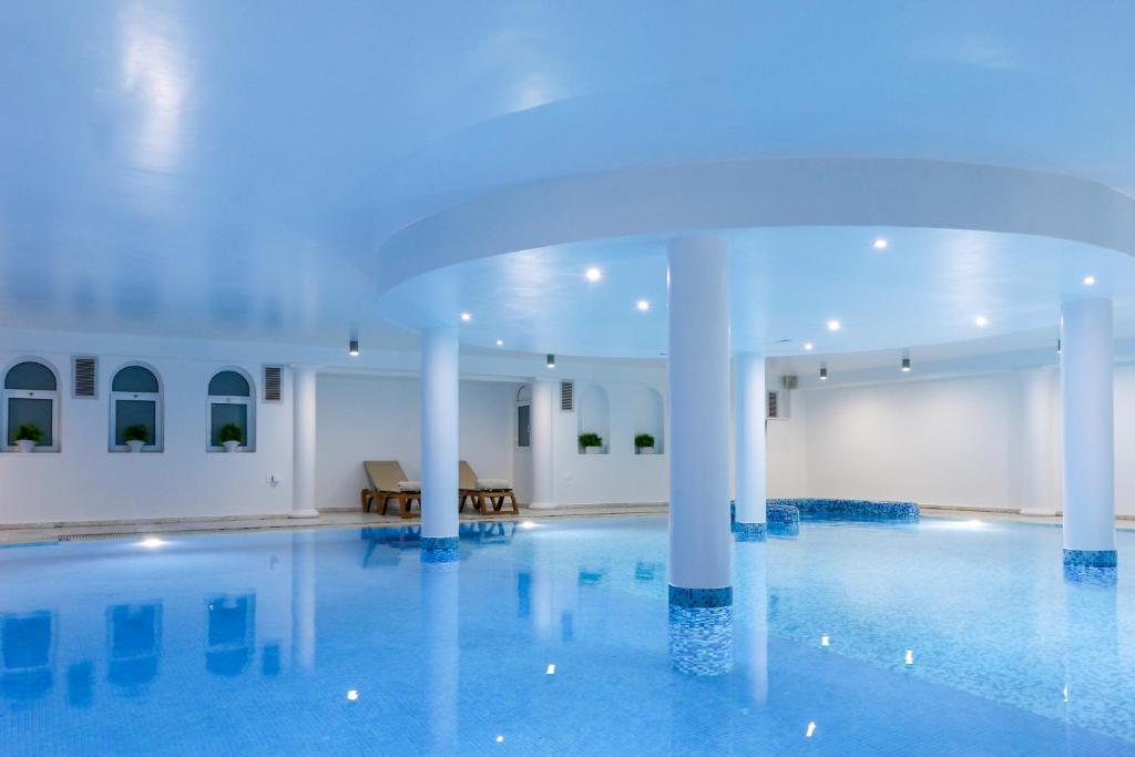 a large swimming pool with white columns in a building at Golden Bay Beach Hotel in Larnaca