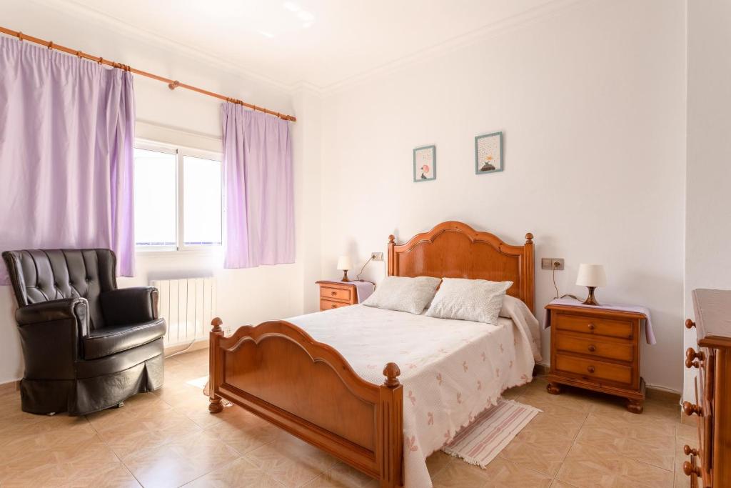ein Schlafzimmer mit einem Bett und einem schwarzen Stuhl in der Unterkunft Apartamento Valle de Abdalajis in Málaga