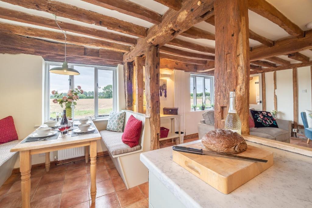 a living room with wooden ceilings and a table at Stylish rural cottage with views over fields and the River Stour - The Granary in Colchester