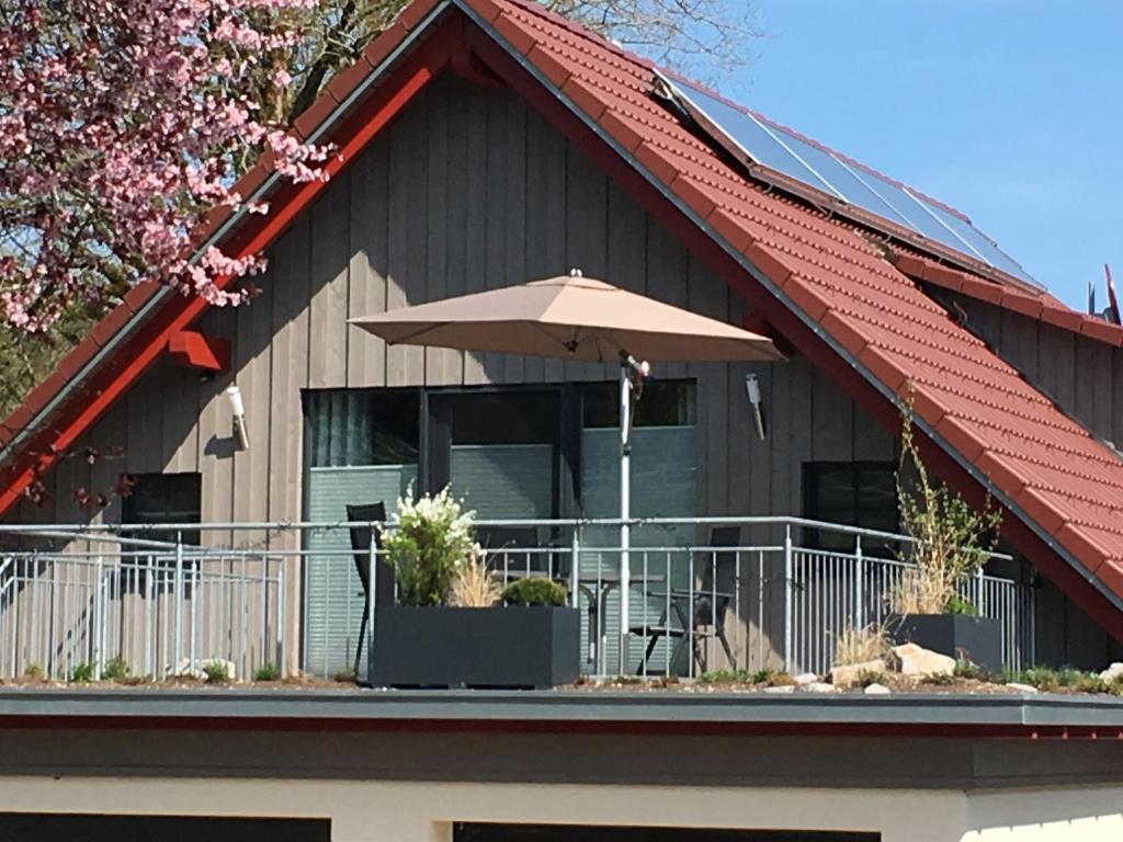 a house with an umbrella on a balcony at Exklusive Ferienwohnung auf dem Romanshof - Schwarzwald Plus Gastgeber in Loßburg