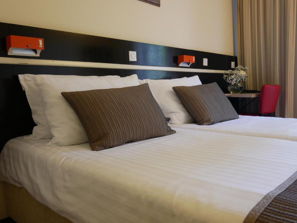 a bedroom with a large bed with white sheets and pillows at Hotel Bellevue in Plitvička Jezera