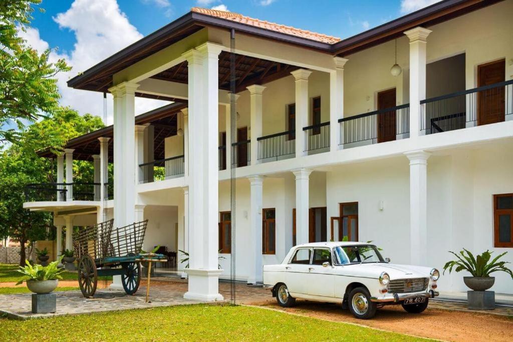 an old white car parked in front of a house at The Notary's House in Makandura