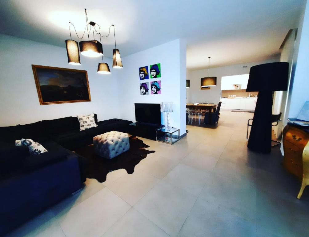 ein Wohnzimmer mit einem schwarzen Sofa und einem TV in der Unterkunft Maison Margot in Acquaviva Picena