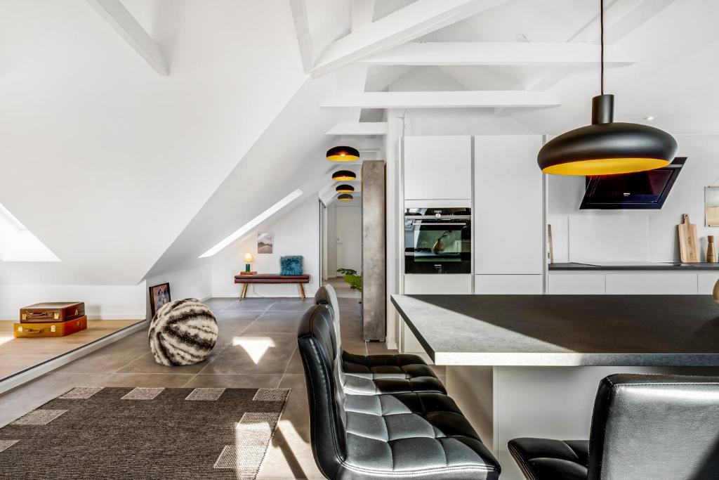a kitchen and living room with black chairs and a counter at aday - Penthouse 3 bedroom - Heart of Aalborg in Aalborg
