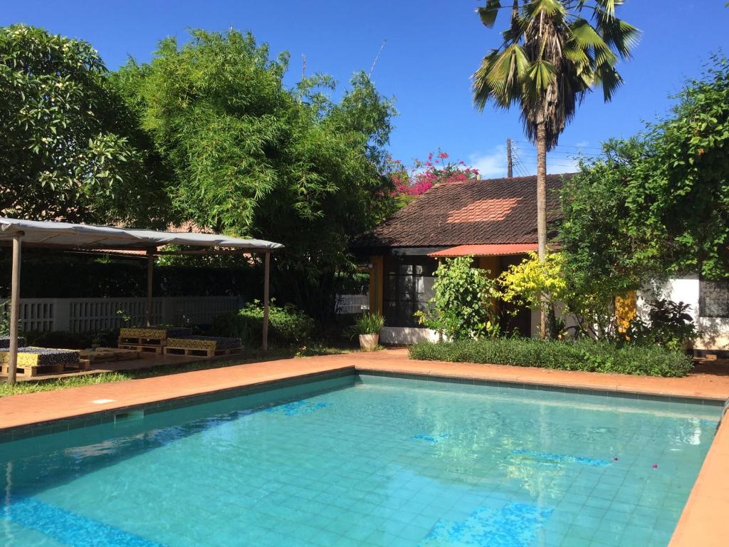 a swimming pool in front of a house with a palm tree at Baobab Village Studio in Dar es Salaam