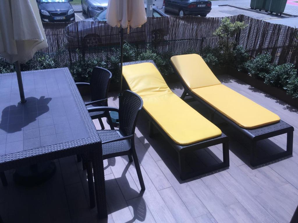una mesa y sillas con cojines amarillos en el patio en My Little Beach House, en Praia da Barra