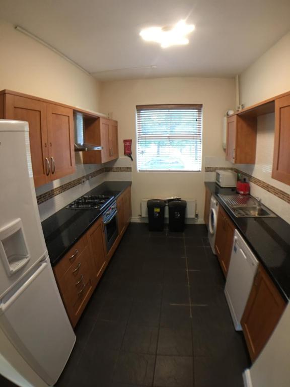 eine Küche mit Holzschränken und schwarzen Arbeitsplatten in der Unterkunft 4 Bedrooms, 3 Bathrooms, Comfy beds, 5 Netflix TVs & VAN PARKING in Boston