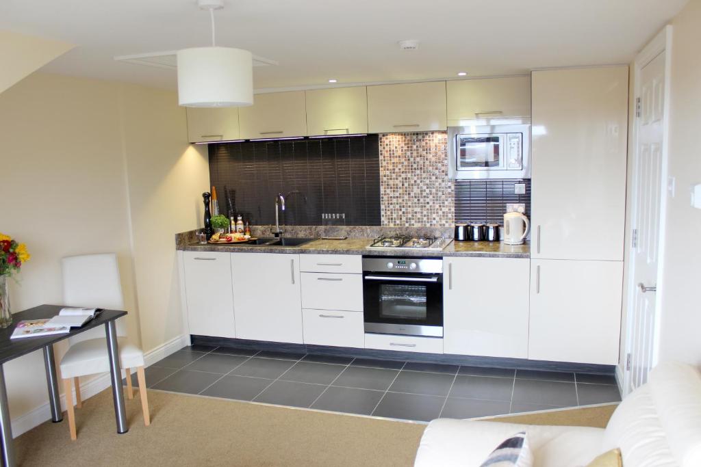 a kitchen with white cabinets and a stove top oven at Silversprings - City Centre Apartments with Parking in Exeter