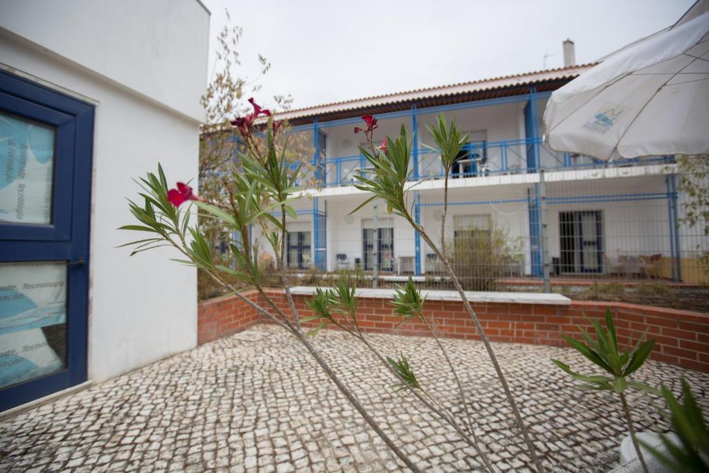 a white building with blue windows and plants in front of it at HI Beja - Pousada de Juventude in Beja