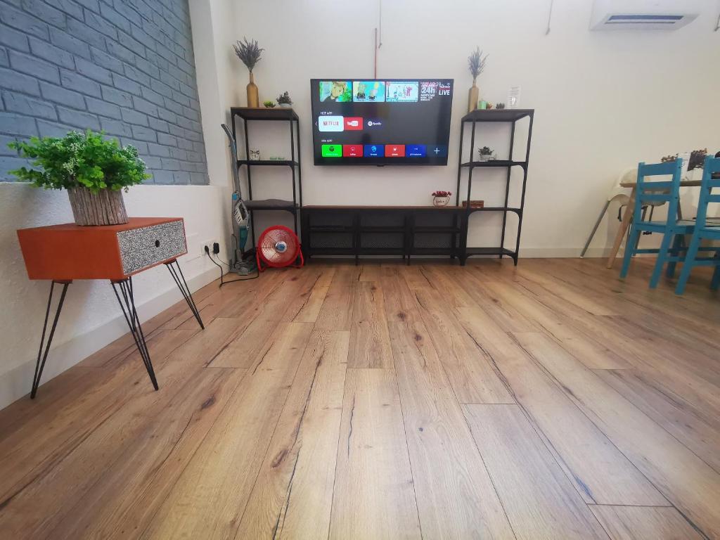 FABRIQ apartment في أليكانتي: غرفة معيشة مع أرضية خشبية وتلفزيون بشاشة مسطحة