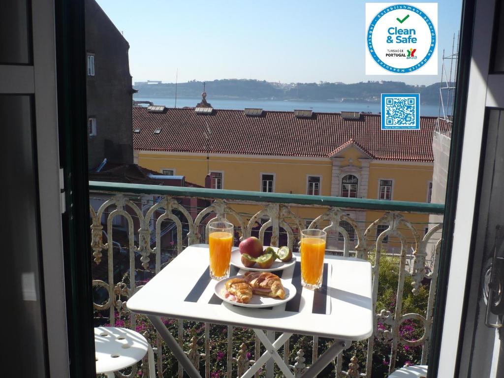 une table avec une assiette de nourriture et deux verres de jus d'orange dans l'établissement Olival 178, à Lisbonne