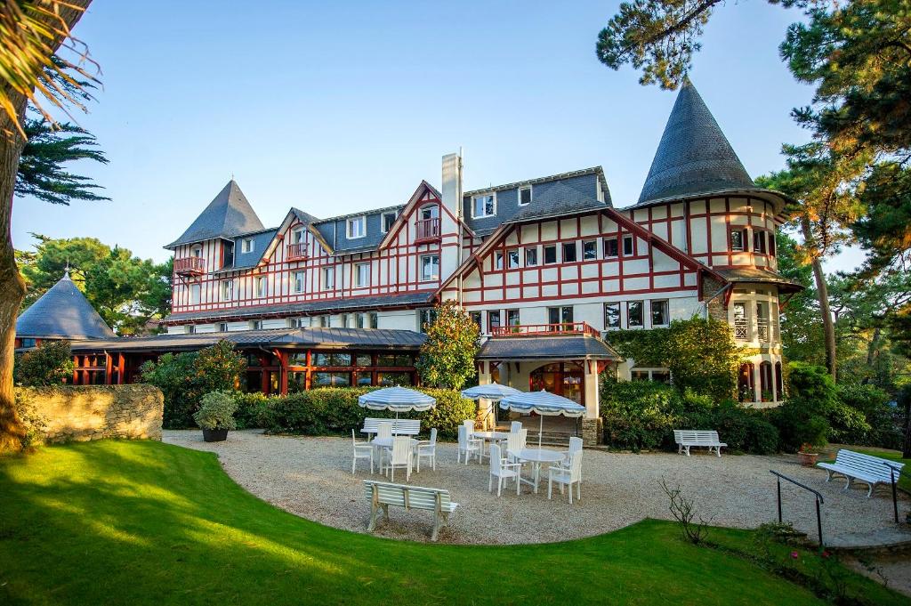 a large building with tables and chairs in front of it at Hôtel Miléade Les Pléïades La Baule in La Baule
