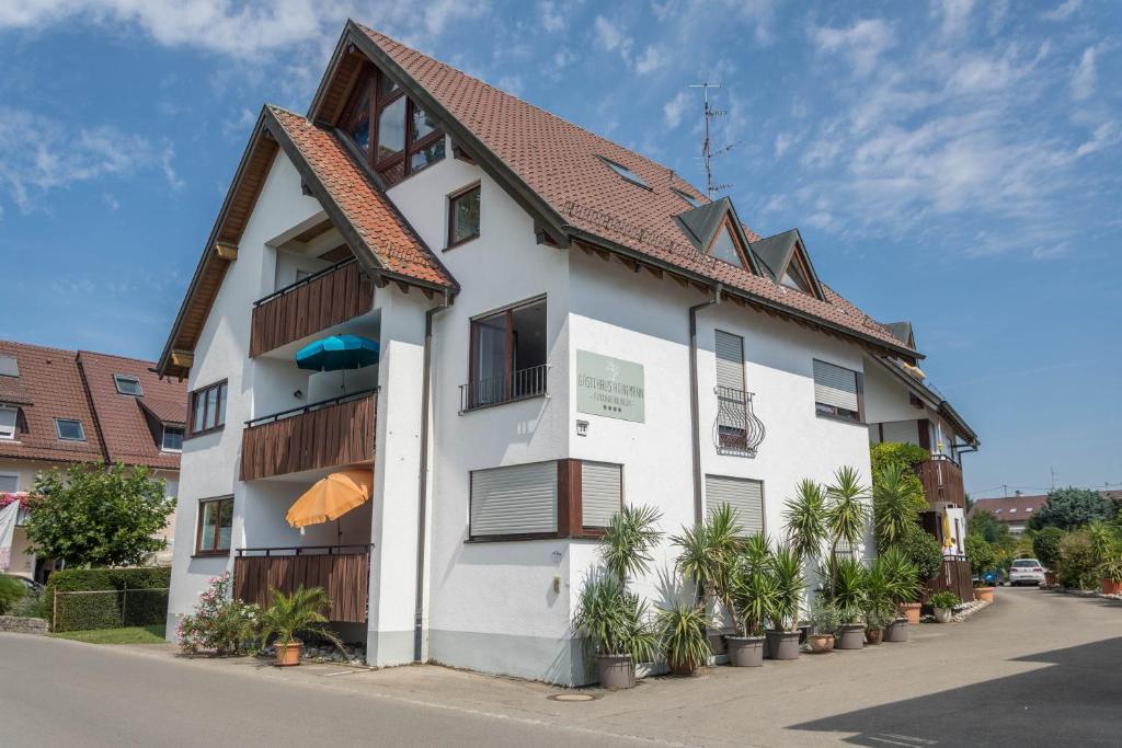 een wit gebouw met een bruin dak bij Gästehaus Heinemann - Eg5 in Langenargen