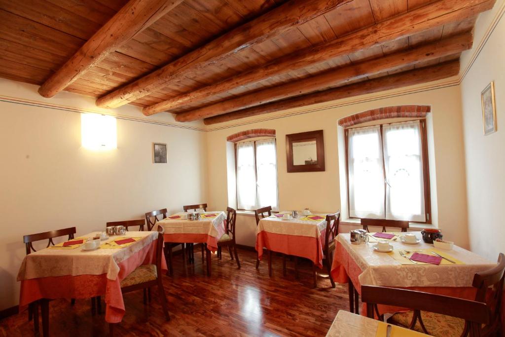 ein Esszimmer mit Tischen, Stühlen und Fenstern in der Unterkunft Locanda da Bepi in Marano di Valpolicella