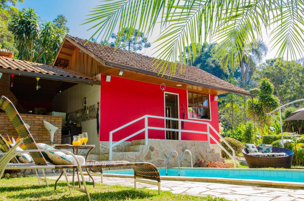 une maison avec une façade rouge à côté d'une piscine dans l'établissement Pousada Refúgio das Aves, à Visconde de Mauá