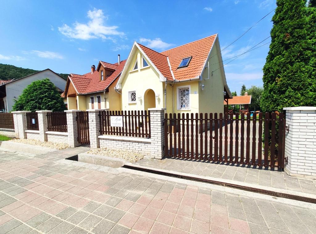 una casa amarilla con una valla de madera en Apollo Vendégház, en Bogács