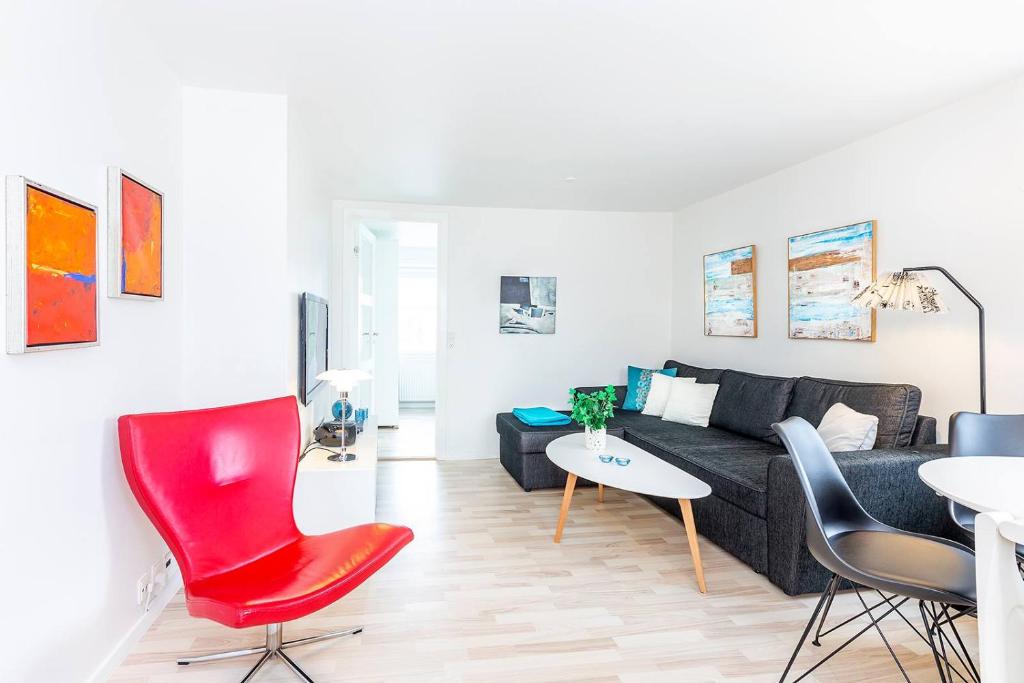 a living room with a black couch and red chairs at In the heart of Tórshavn in Tórshavn