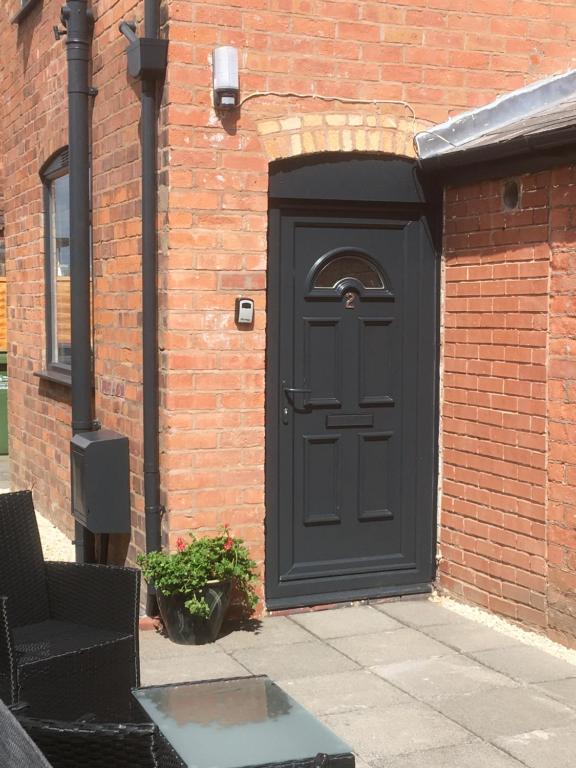 una puerta negra en el lateral de un edificio de ladrillo en Cosy and Peaceful Maisonette with Terrace, Kidderminster, en Kidderminster