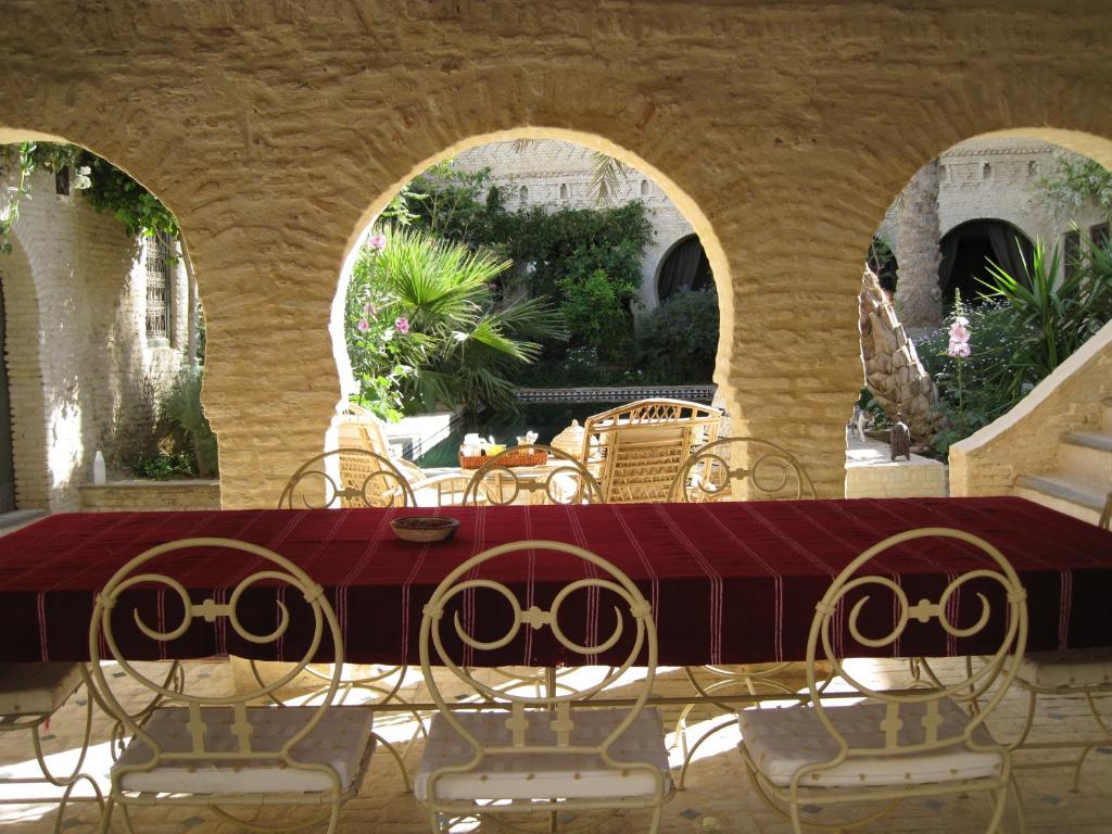 una mesa y sillas en un patio con 2 arcos en DAR NEJMA, en Tozeur