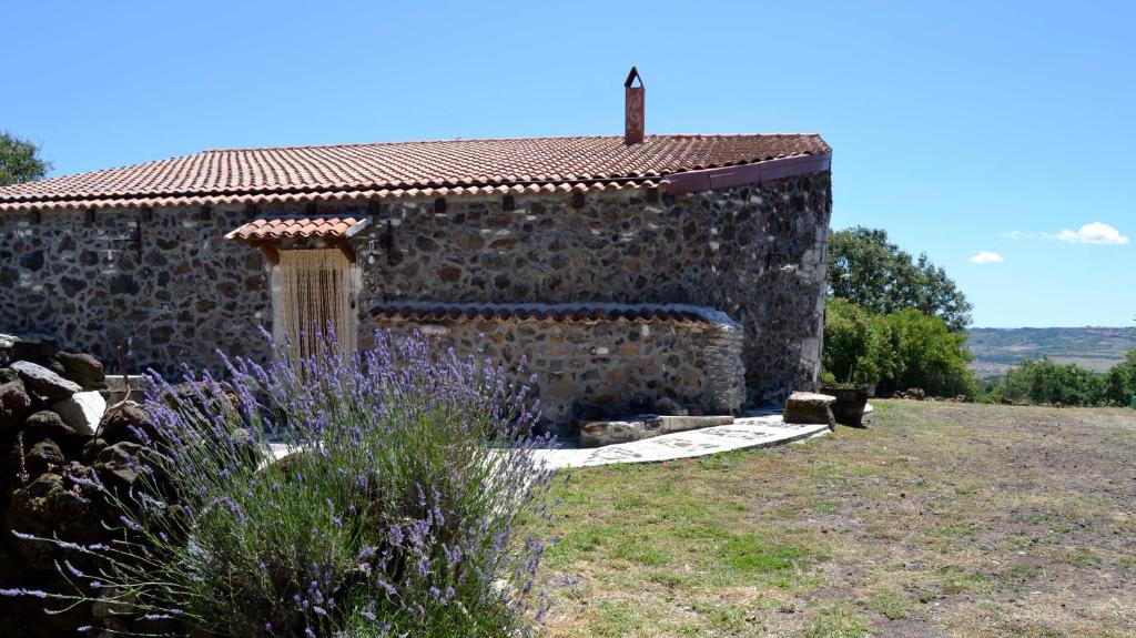 una casa in pietra con giardino e fiori di fronte di Su Montiju a Cheremule