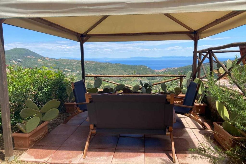 a chair under a tent with a view of the mountains at Magic Elba & Mindfulness Apartment in Rio nellʼElba