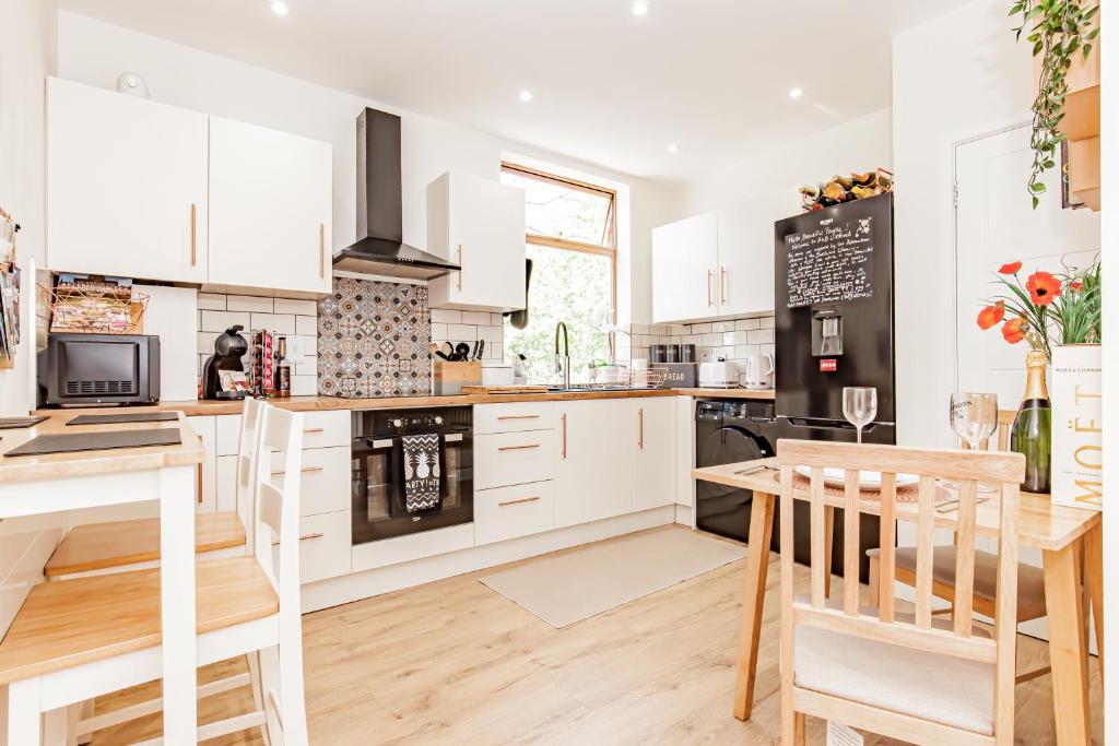 a kitchen with white cabinets and a table and chairs at A'nB Oxford LUX 2-Bedroom plus private parking 5-STAR Central OX1 in Oxford