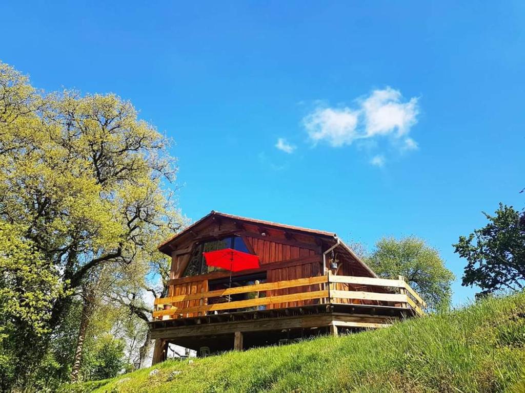 a tree house on a hill with a red umbrella at Le Refuge De L'Ourse in Anla