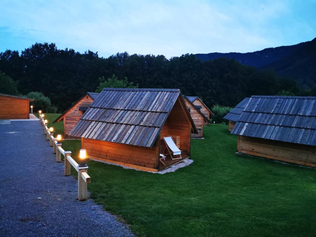 a row of huts with solar panels on the grass at Small wooden houses and Apartments Zgornja Dobrava in Radovljica