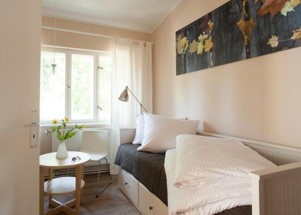 ein kleines Schlafzimmer mit einem Bett und einem Tisch in der Unterkunft Villa Weißensee in Potsdam