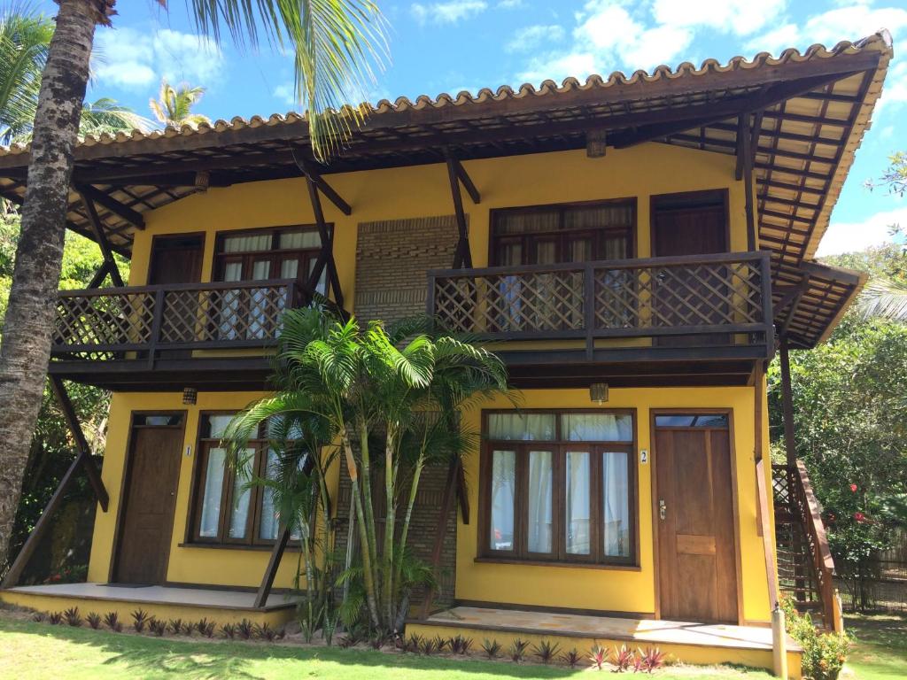 Maison jaune avec balcon et palmiers dans l'établissement Village em Taipu Fora - Apartamento pé na areia, à Marau