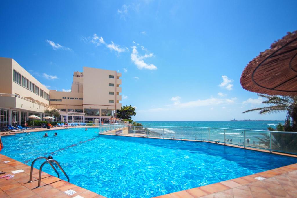 a swimming pool with the ocean in the background at Hotel Servigroup Galua in La Manga del Mar Menor