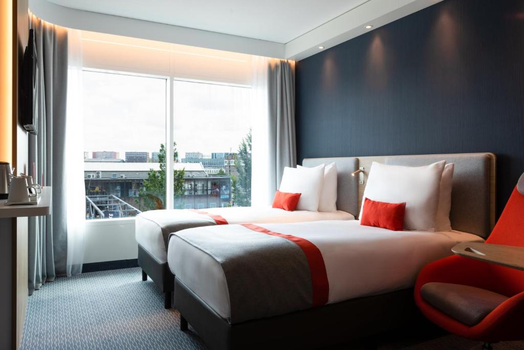 two beds in a hotel room with a window at Holiday Inn Express Amsterdam - North Riverside by IHG in Amsterdam