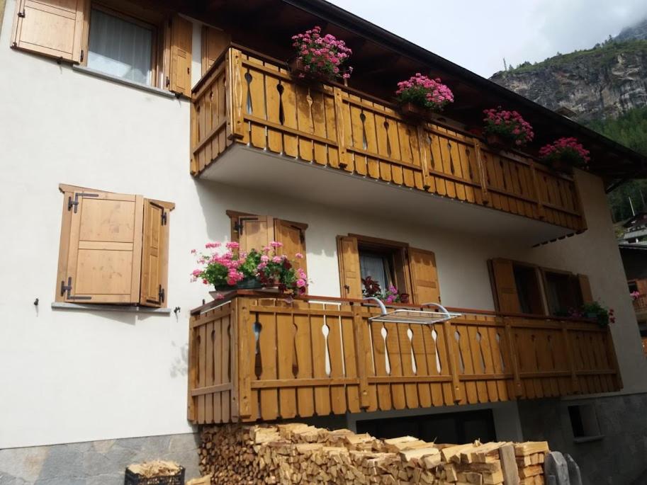 une maison dotée d'un balcon en bois et de fleurs. dans l'établissement Appartamento Genziana, à Isolaccia