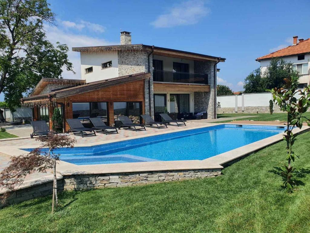 une villa avec une piscine en face d'une maison dans l'établissement Vila Antik, à Garmen